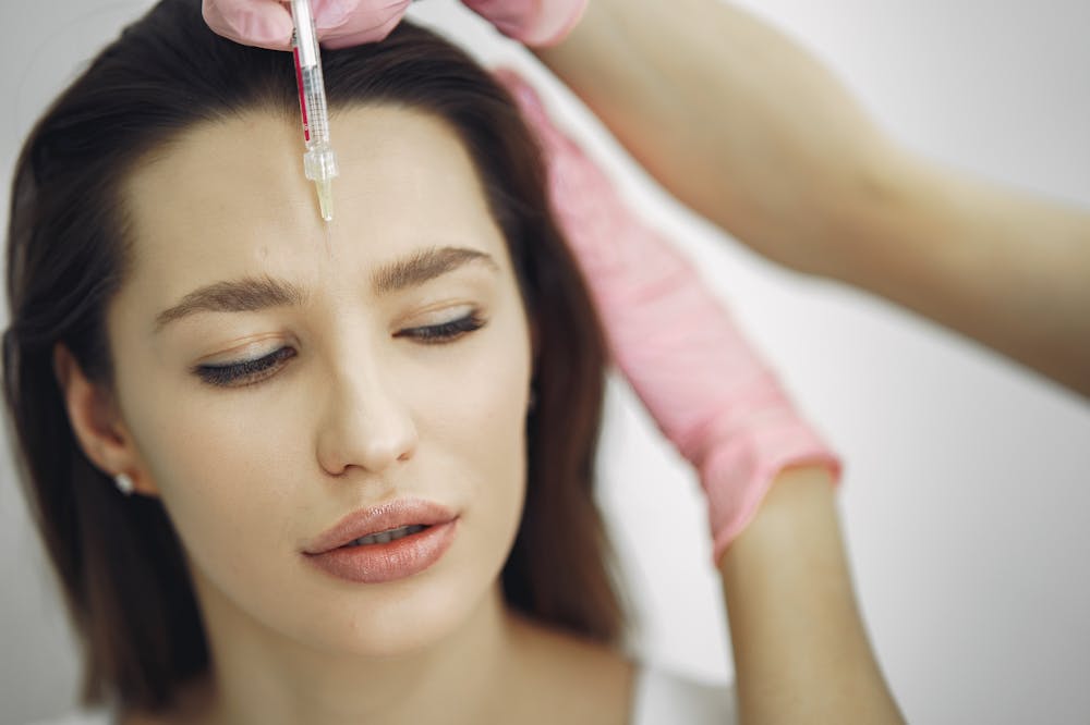 Paciente séria, recebendo aplicação estética de uma pessoa usando luvas cor de rosa. Ilustração do texto sobre mercado de estética.