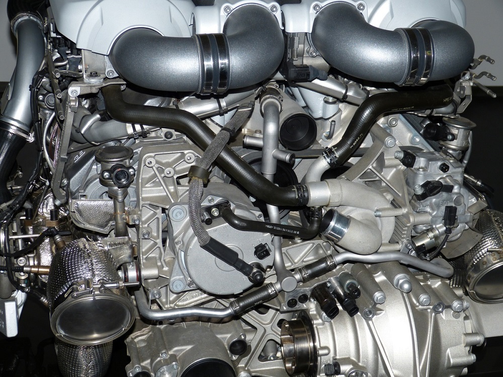 Motor de carro com várias mangueiras e tubos nas cores preta e cinza. Imagem ilustrativa do texto franquia de auto peças.