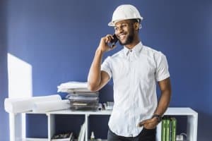 Homem usando camisa branca e capacete EPI de construção em escritório. Ilustração do texto sobre franquia de material de construção.
