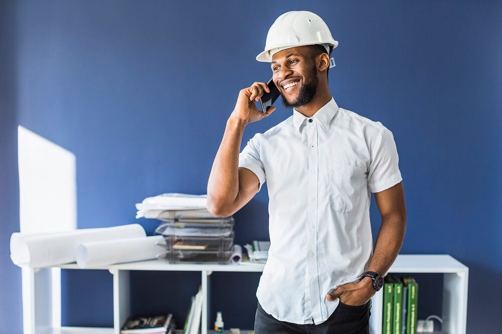 Homem usando camisa branca e capacete EPI de construção em escritório. Ilustração do texto sobre franquia de material de construção.