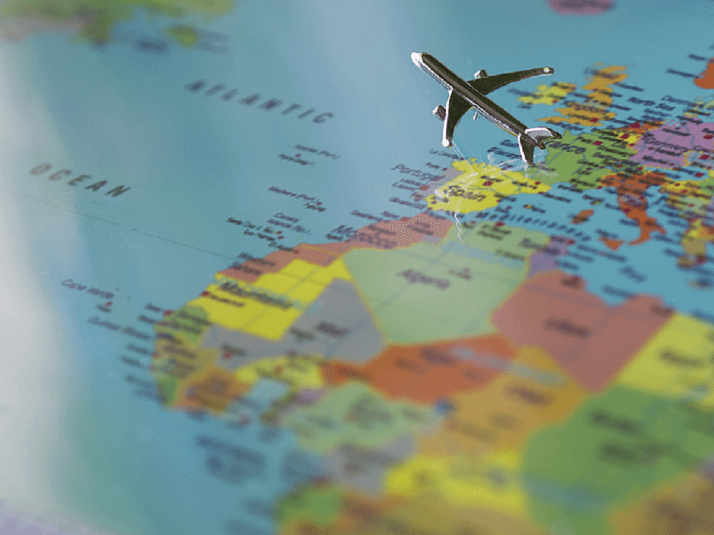 Miniatura de um avião voando sobre um mapa mundi; imagem ilustrativa do texto turismo mercado de franquias.