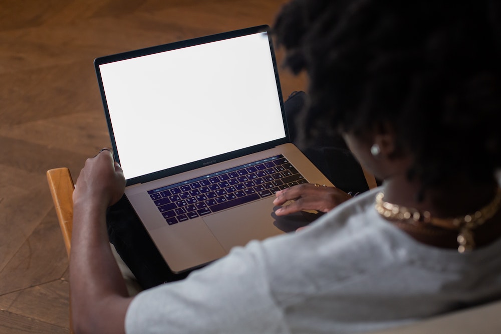 Mulher de costas usando uma blusa branca e trabalhando em um computador. Ilustração do texto sobre franquia de vendas online.