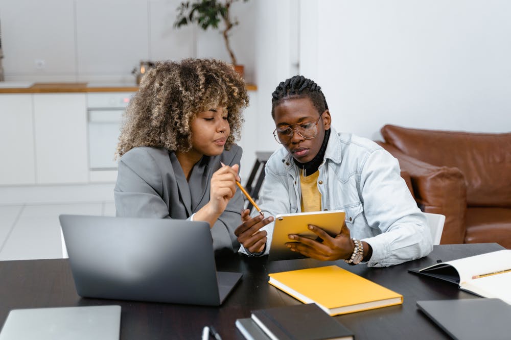 Homem e mulher conversando, em mesa de escritório com pasta amarela em cima. Ilustração do texto sobre conheça 5 vantagens de investir em uma franquia de serviço.