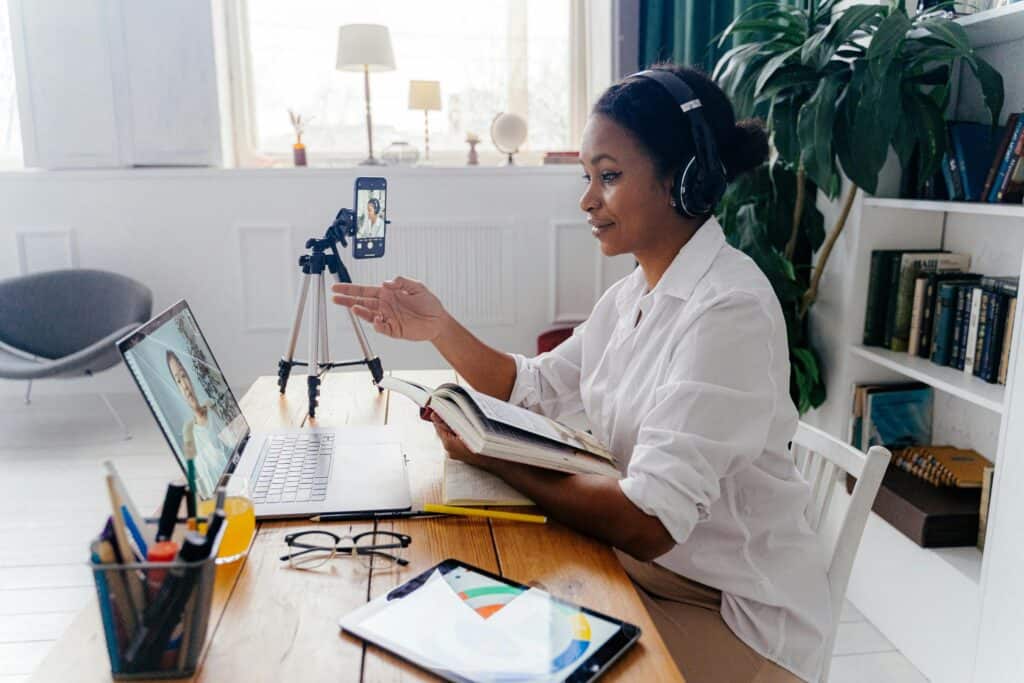 Mulher sorridente, usando camisa branca, enquanto está em teleconferência em seu notebook. Ilustração do texto sobre empreendedorismo digital.