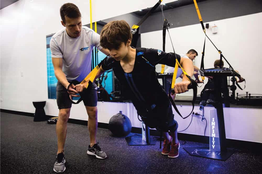 As 128 melhores franquias baratas em 2026 - veja a lista Personal trainer ajudando uma criança a fazer exercício físico em uma unidade da E-Fit.