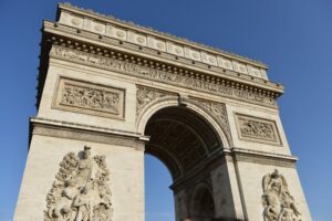 Arco do Triunfo em Paris, se destacando sob céu azul. Ilustração do texto sobre franquias de turismo.