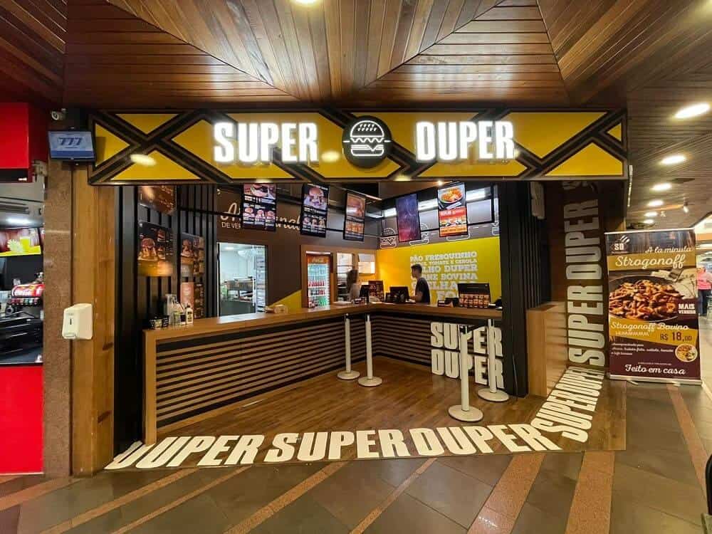 As 128 melhores franquias baratas em 2026 - veja a lista Fachada amarela e área interna de uma loja Super Duper, franquia.