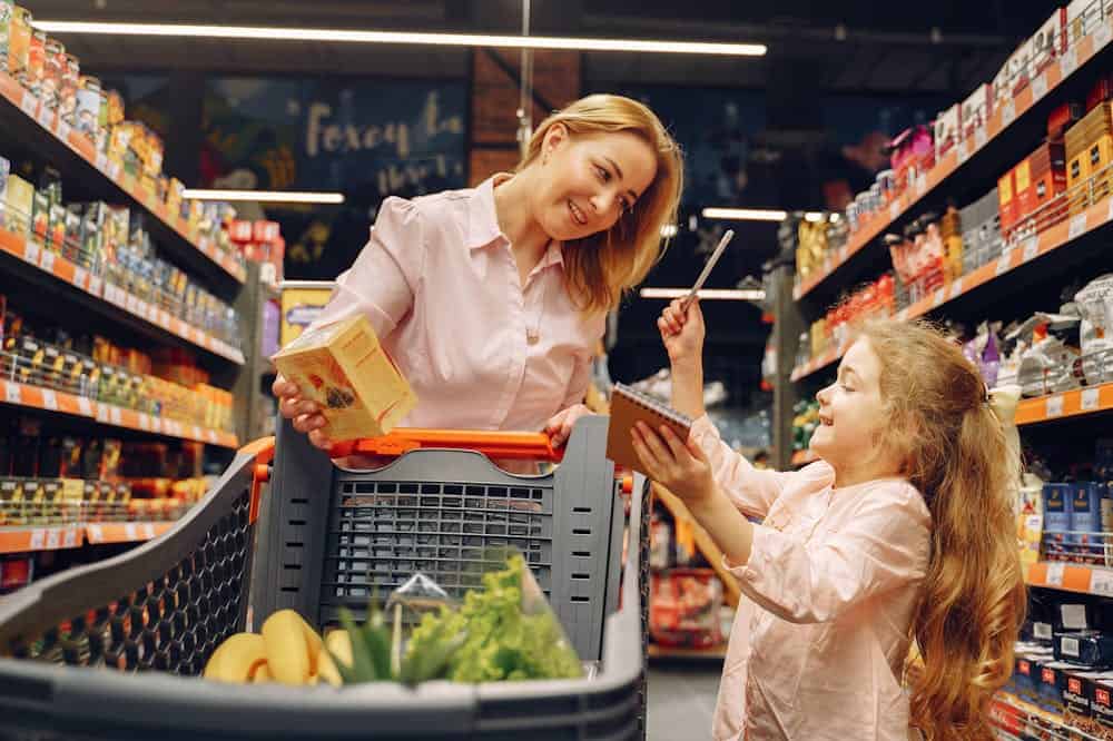 Mulher sorridente, usando blusa social cor de rosa, fazendo compras com a filha. Ilustração do texto sobre setores que mais crescem no Brasil.
