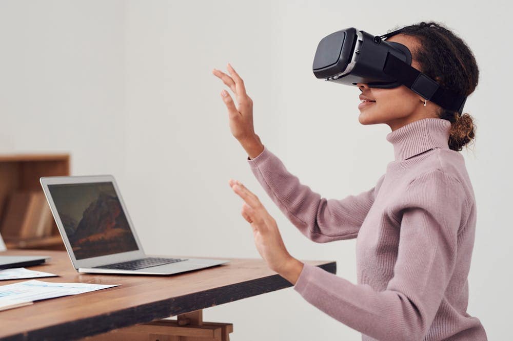 Mulher sorridente, usando óculos de realidade virtual preto. Ilustração do texto sobre negócios do futuro.