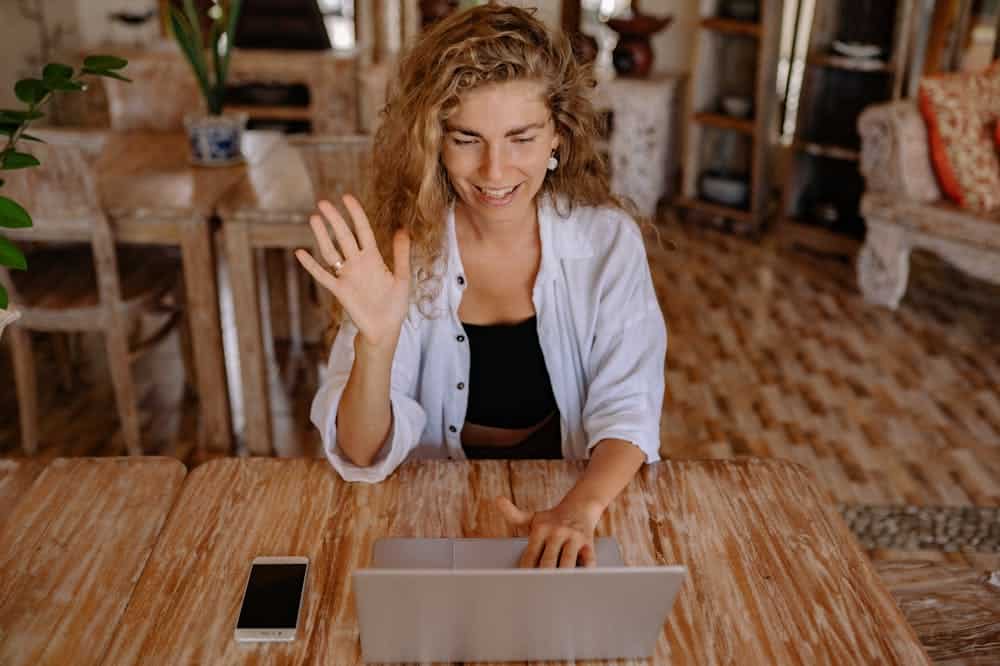 Mulher sorridente, usando blusa social lilás, enquanto trabalha na frente de um notebook. Ilustração do texto sobre empreendedor de sucesso.