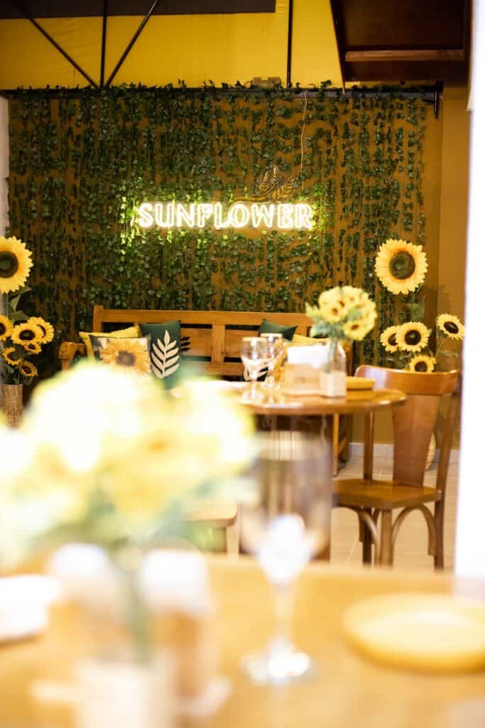 As 128 melhores franquias baratas em 2026 - veja a lista Mesas no restaurante Sunflower e girassóis ao fundo.