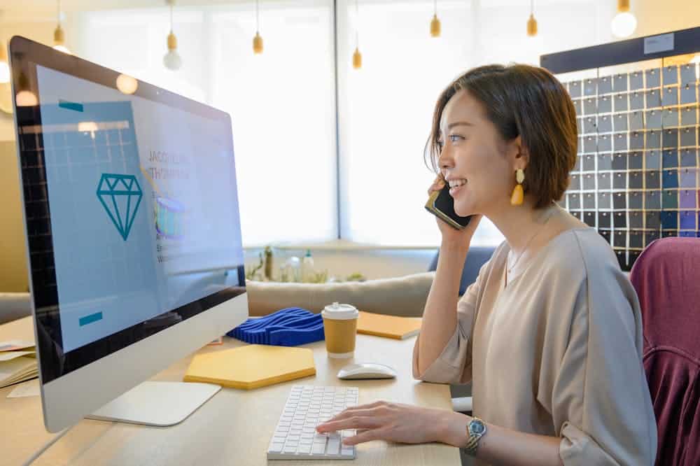 Mulher sorridente ao telefone, enquanto observa o notebook. Ilustração do texto sobre maiores franquias do Brasil.