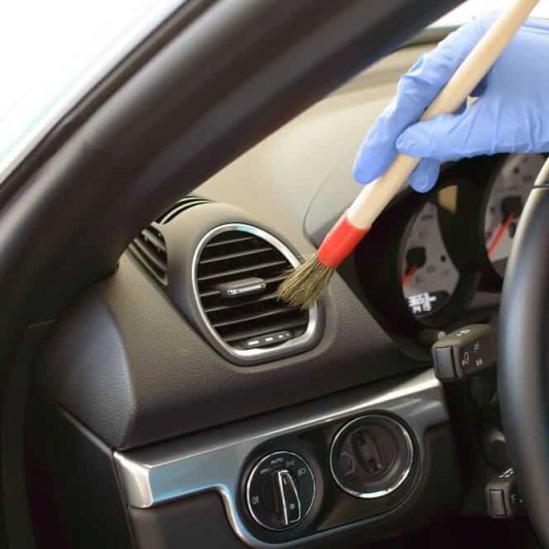 Mão masculina limpando painel do carro com pincel