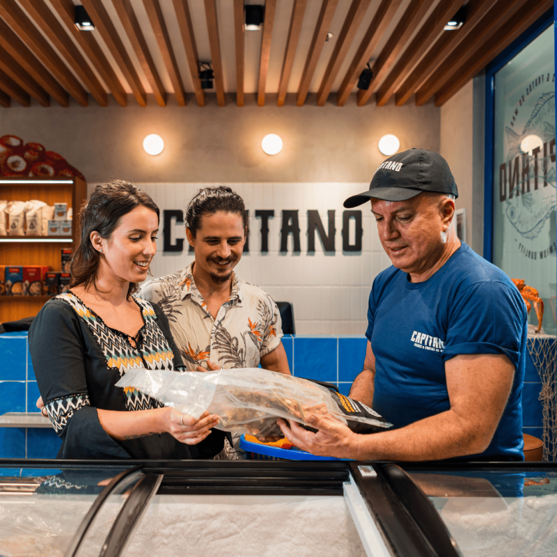 Clientes com pescado sendo apresentado para atendentes.
