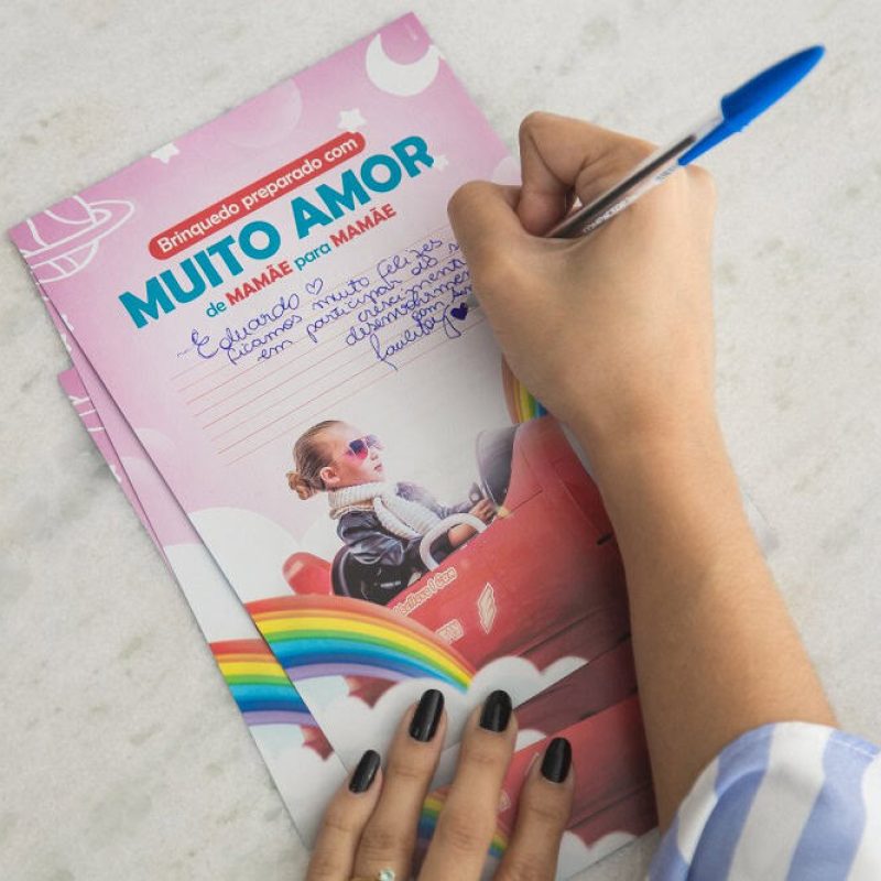 Mão de mulher escrevendo recado que vai junto aos brinquedos Facilitoy entregues aos clientes.