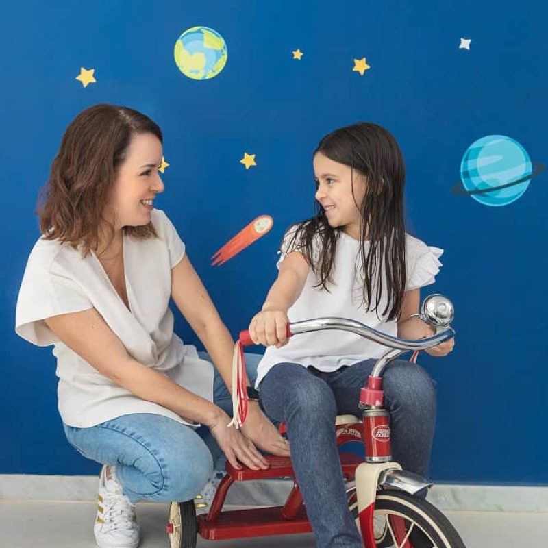Isabel Tunas, fundadora da Facilitoy, com uma criança brincando de triciclo.