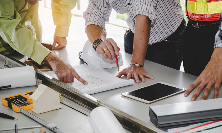 A construction team discusses an asbestos building plan with a blueprint.
