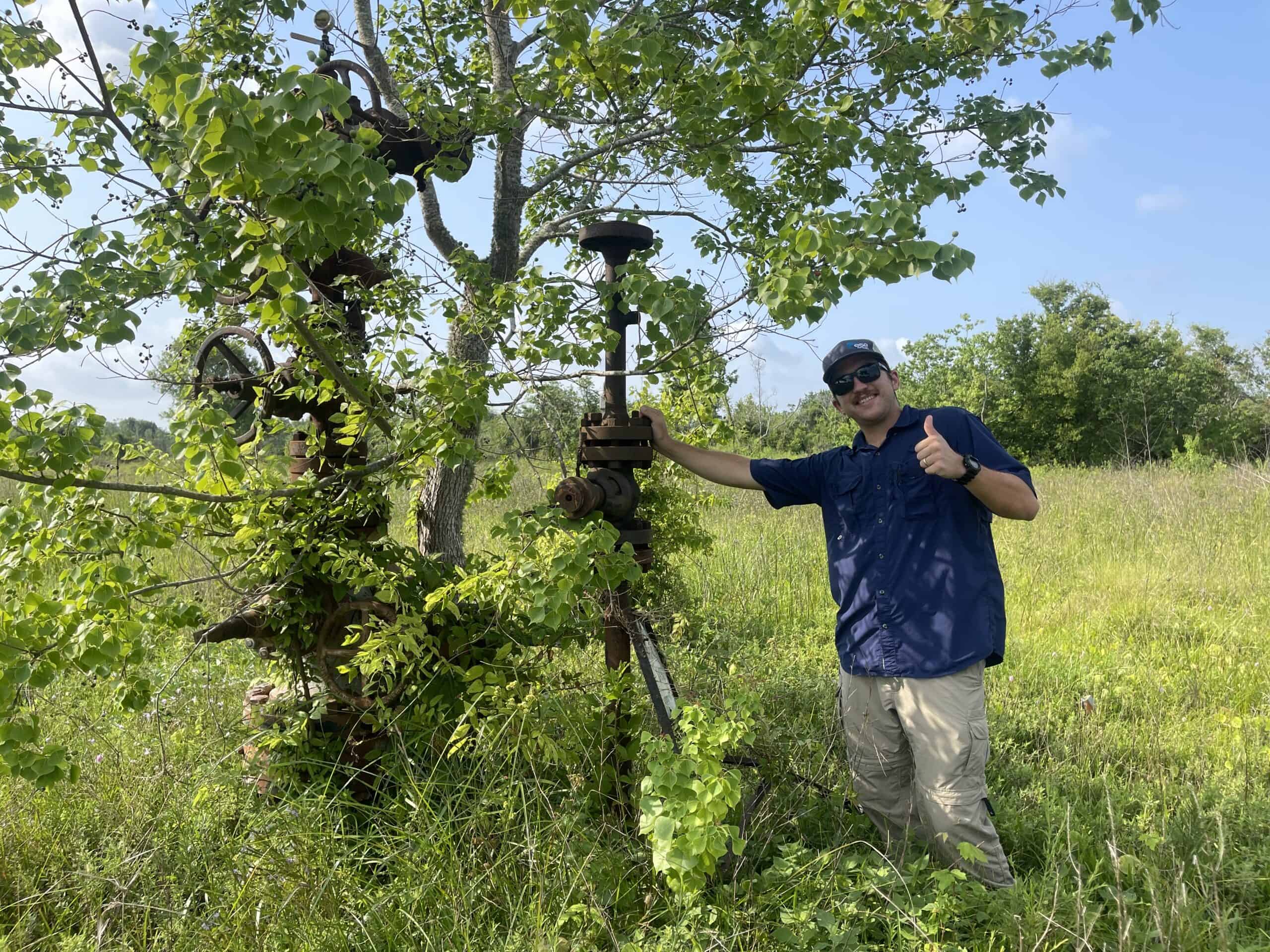 A professional wearing a hard hat and gloves is collecting water samples from a city runoff stream.</p>
<p>