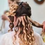 Close-up of hairstylist perfecting curls on a womans hair in a salon setting.