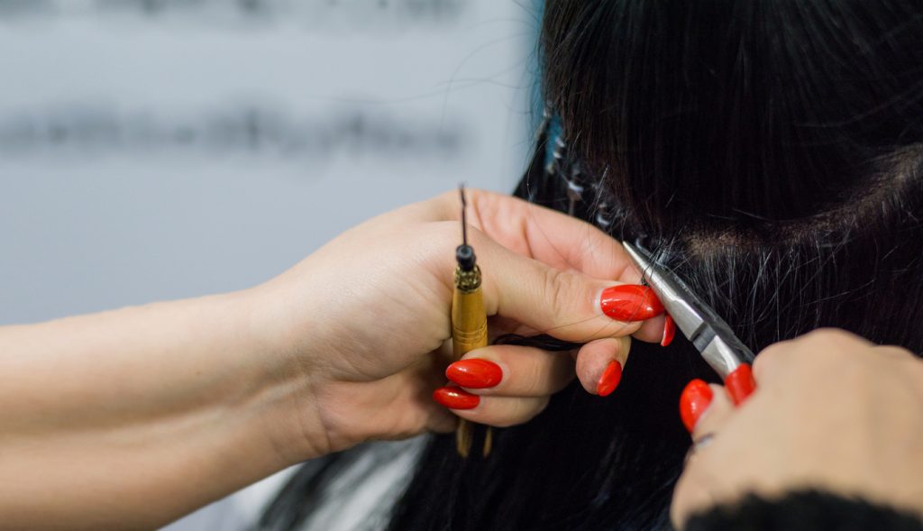 Professional woman applying hair extensions with different types of grips.