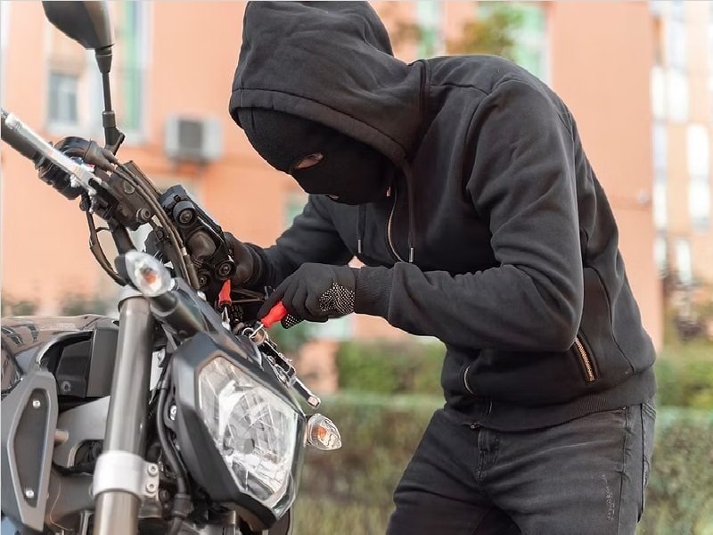 Homem com capuz roubando moto, destacando a importância do rastreamento em 2025.