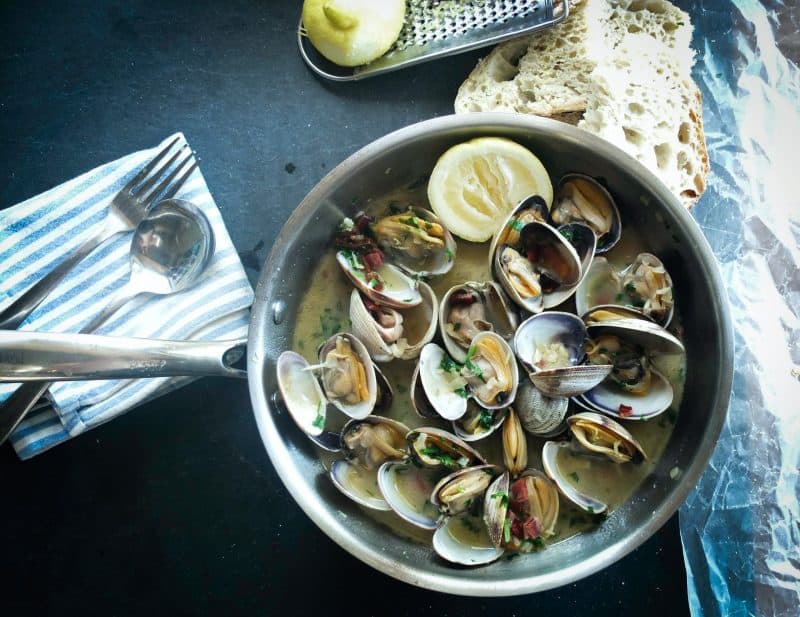 Freshly cooked New Brunswick steamed mussels served with lemon slices, bread, and herbs, showcasing the region's delicious seafood cuisine and culinary experiences.