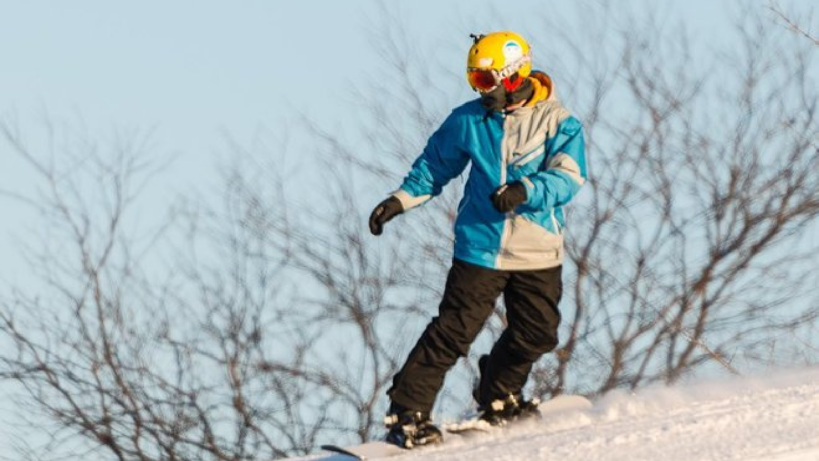 Child skiing in Elgin Area with snow-covered landscape and bare trees in background.
