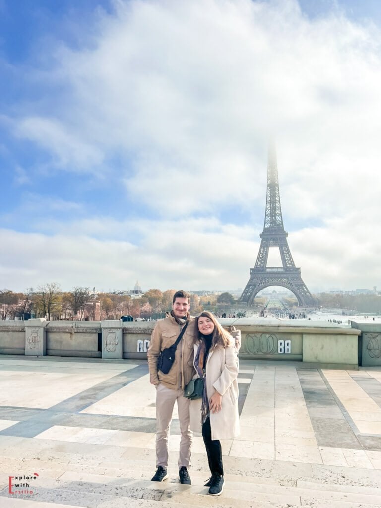 a couple posing in front of the eiffel tower on a sunny day in paris, at the trocadero viewpoint
