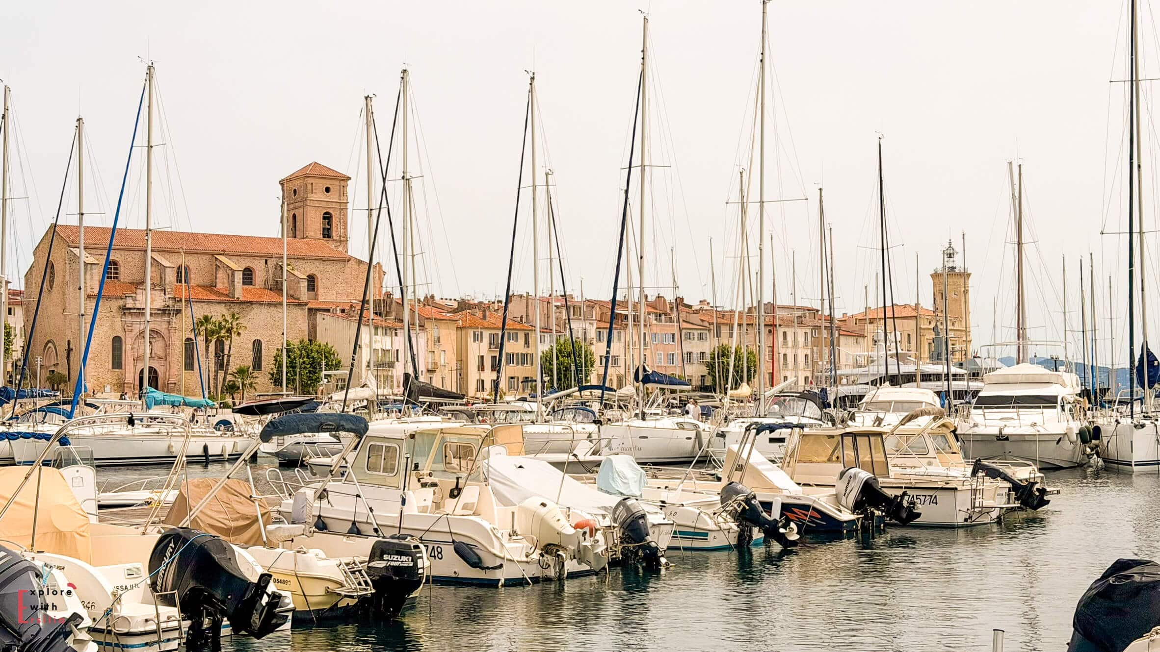 Sailboats and yachts docked in La Ciotat marina with historic waterfront buildings behind them.