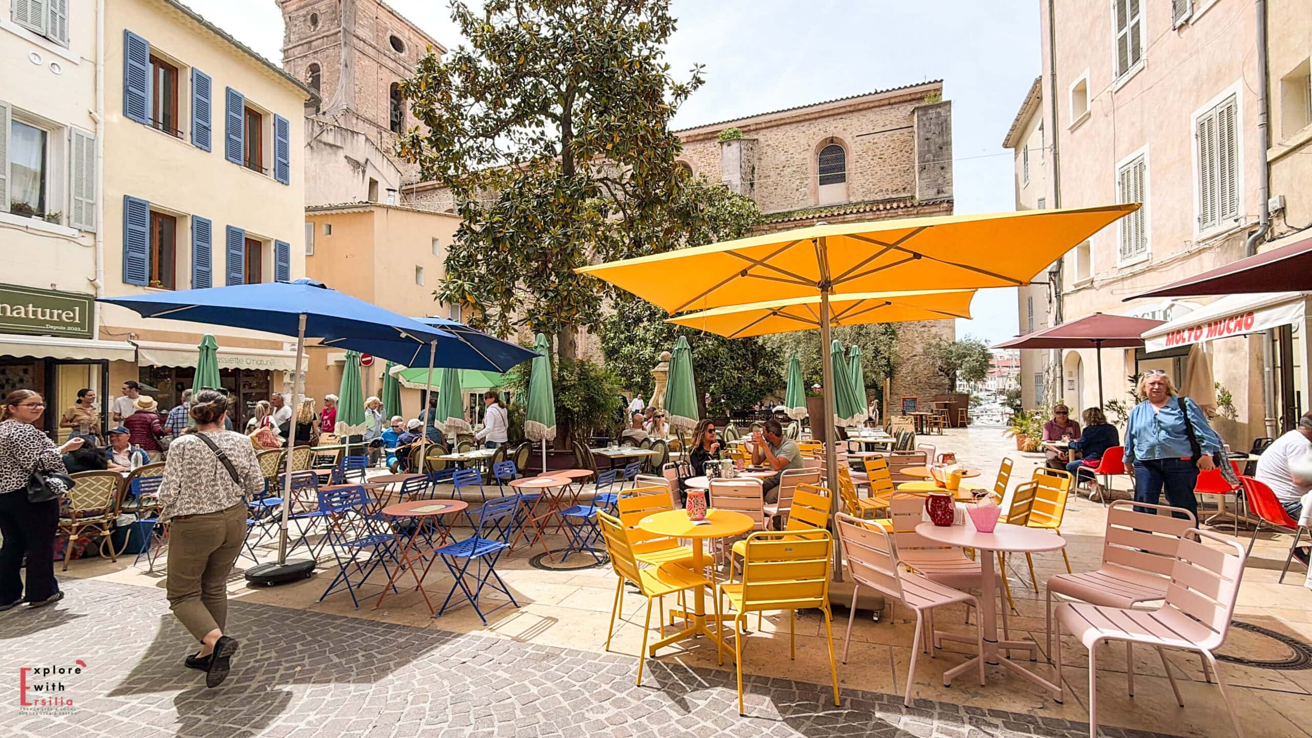 Outdoor restaurant terrace with colorful umbrellas and tables in Place Sadi Carnot, La Ciotat.