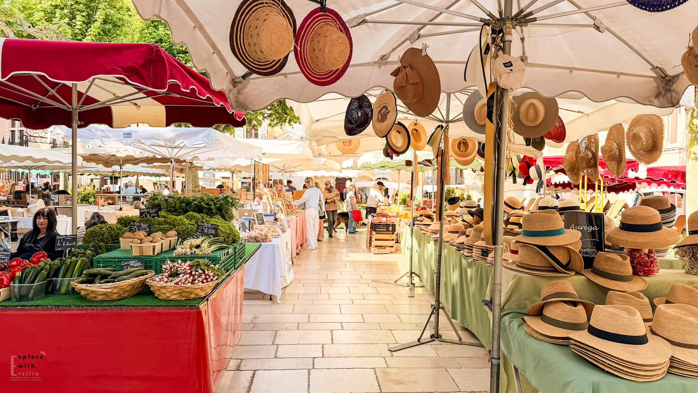 Cassis market stalls displaying fresh produce, local foods, and baskets beneath colorful awnings. Visiting the market is one of the best things to do in Cassis.