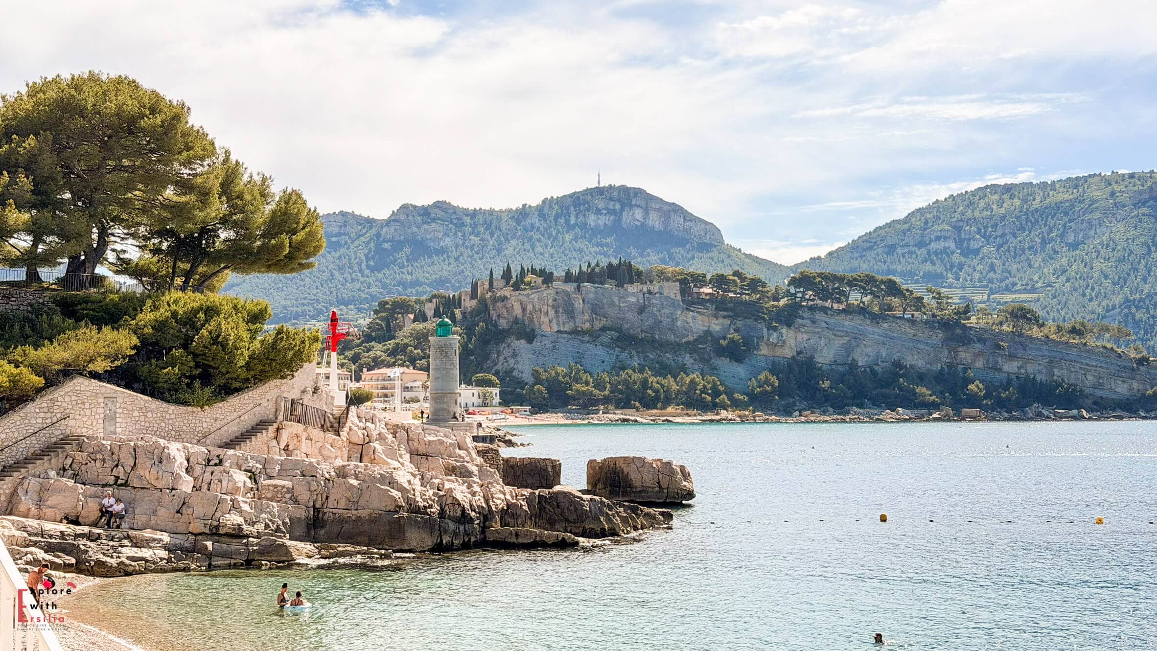 Rocky shoreline and turquoise water near Plage du Bestouan with hills and coastal scenery stretching across the bay.