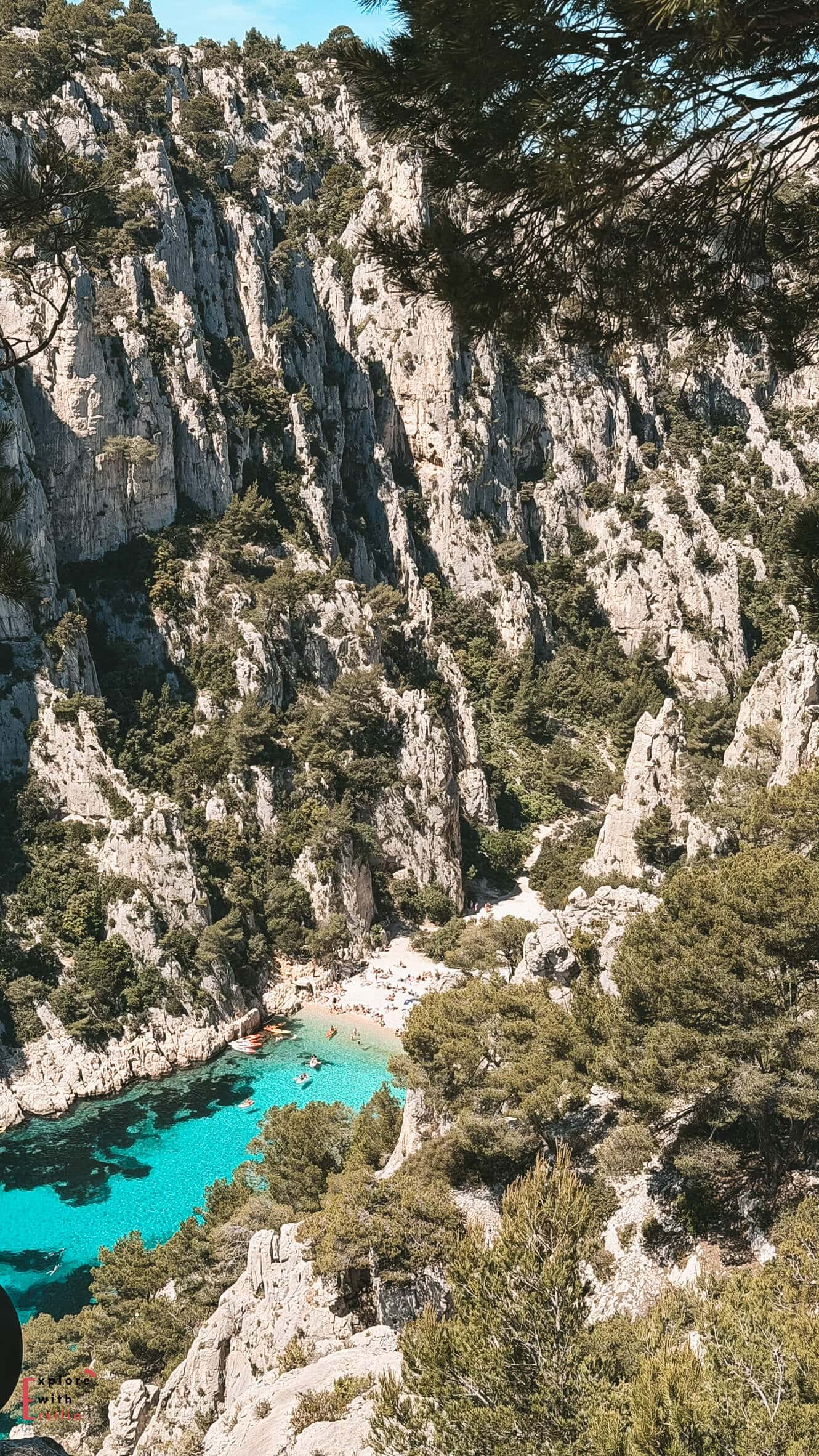 Beach at Calanque d’En-Vau with visitors relaxing beside clear water enclosed by dramatic limestone cliffs.