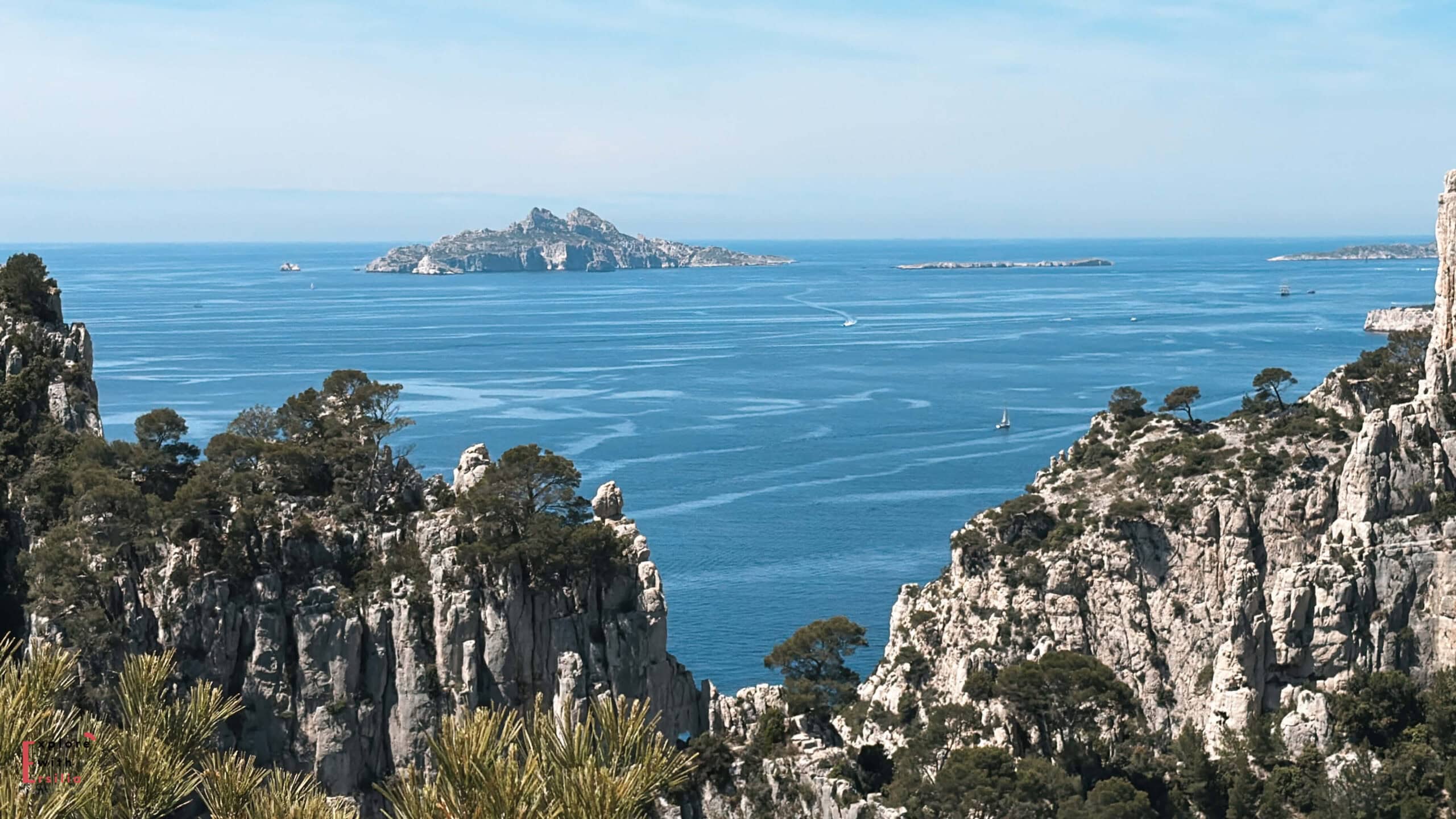 Elevated viewpoint overlooking steep white cliffs and bright turquoise water in Calanques National Park.