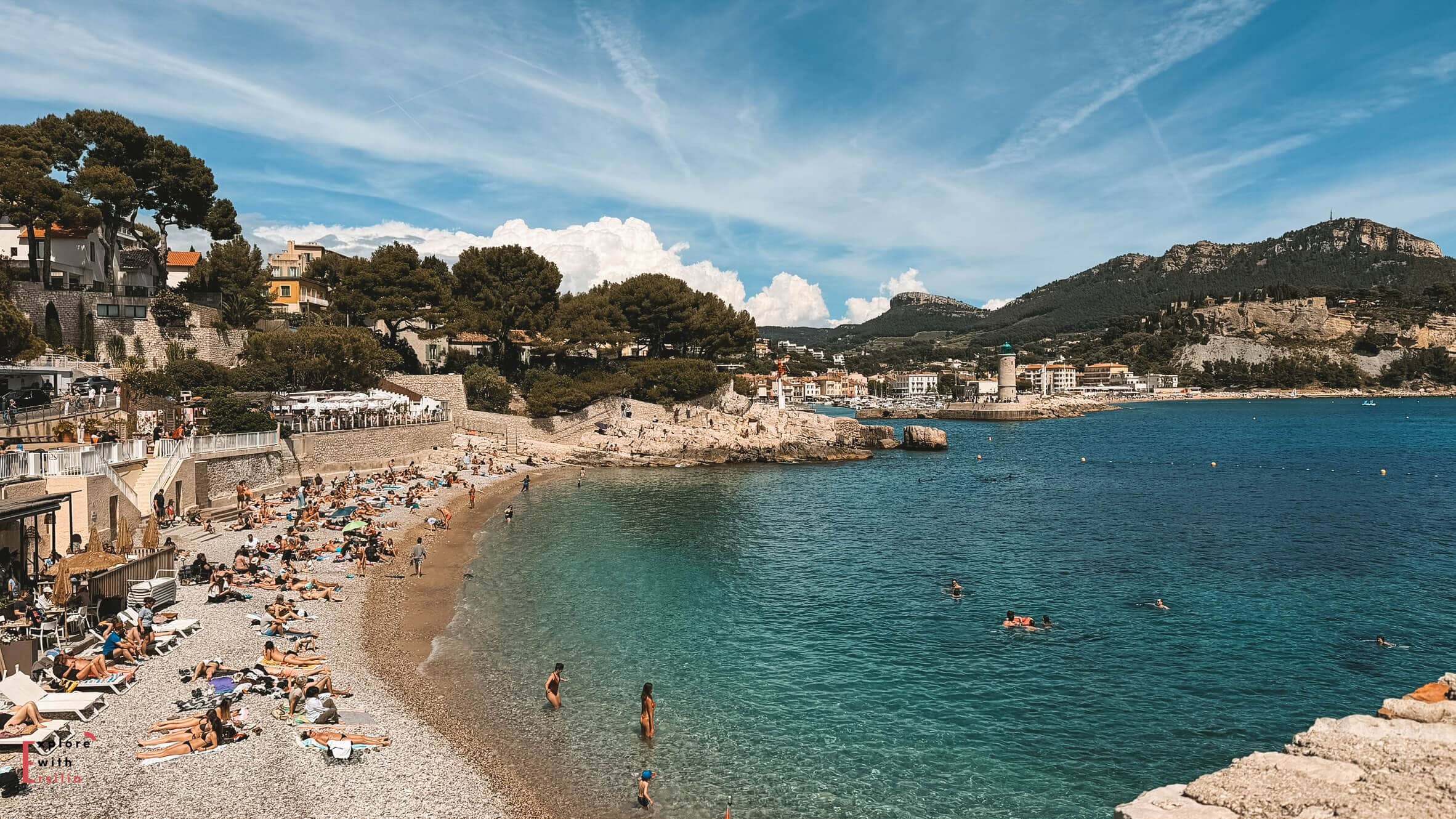 Plage du Bestouan viewed from above with turquoise water, beach visitors, and cliffs surrounding the bay.