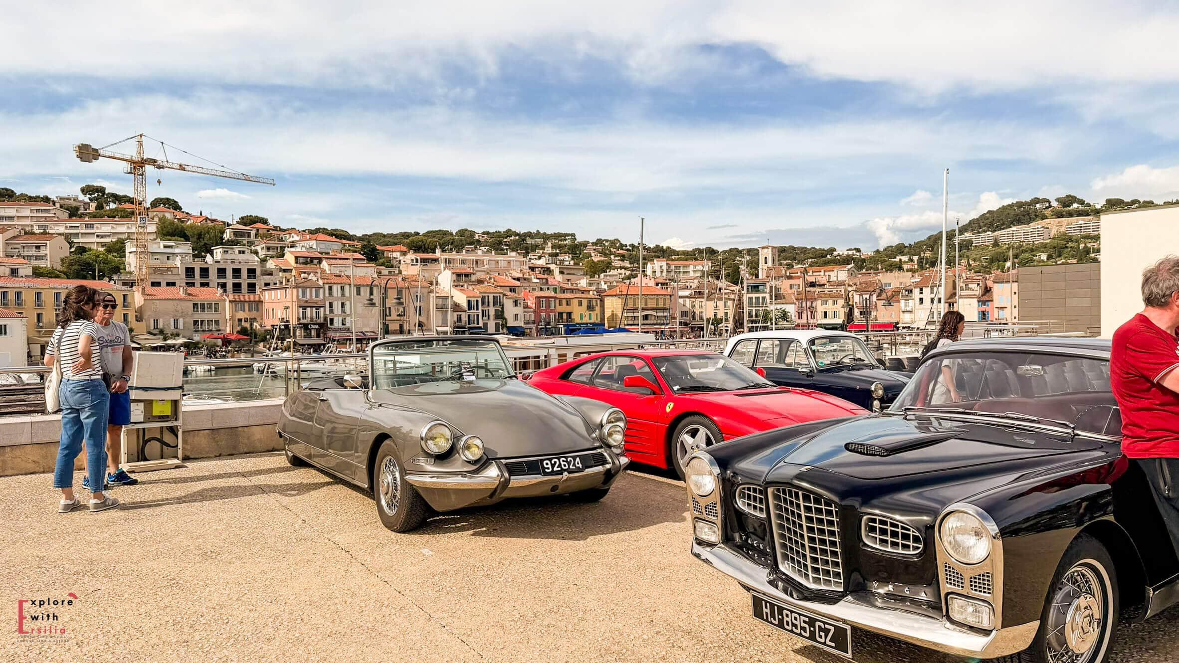 Collection of vintage cars displayed along the Cassis waterfront during a local event beside the harbor.