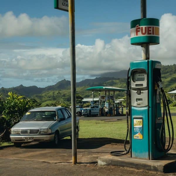 Fuel station in Fiji with scenic mountain backdrop and parked car.