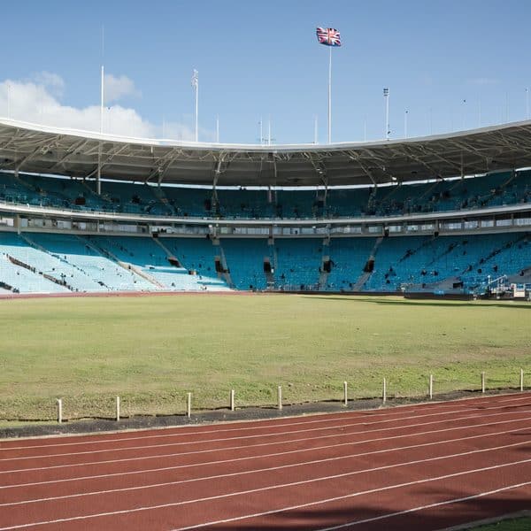 Fiji Stadium with empty field and blue seating under clear sky.