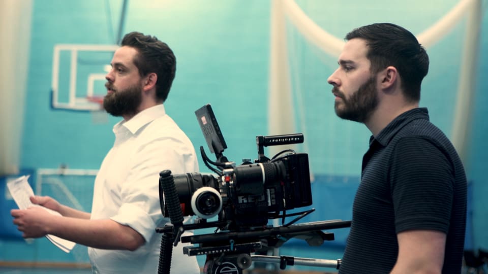 Cinematic film crew filming in gymnasium for documentary production.