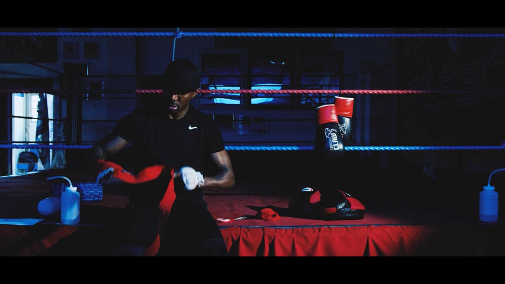 Boxer preparing in a dimly lit boxing gym, focused and ready for training or a match.