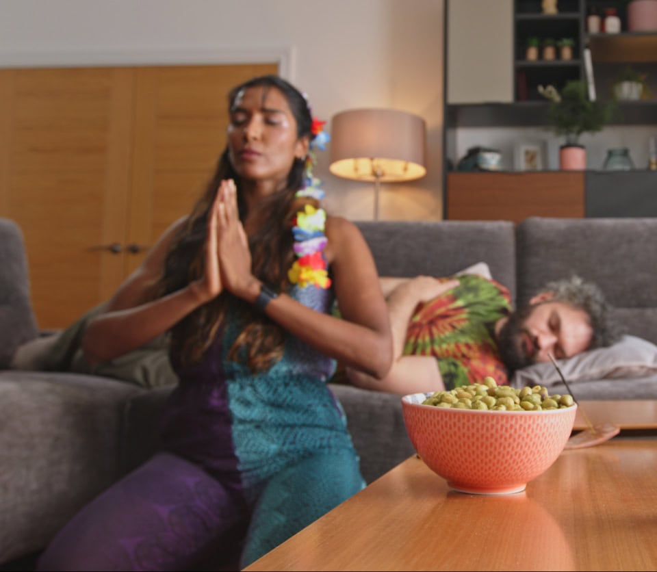Meditating woman in colorful attire during a relaxing yoga session at home.