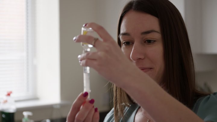 Focused woman preparing vaccine in clinical setting, healthcare, medical, immunisation, professional medical workers, health awareness.