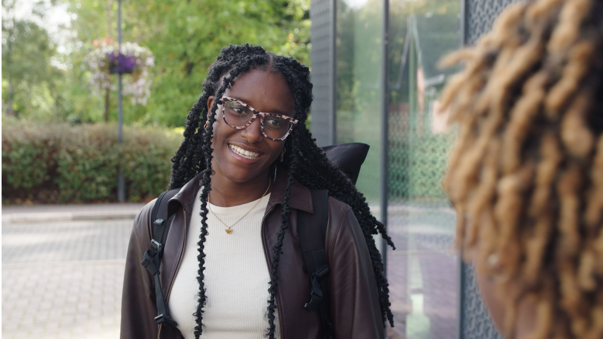 Diverse woman with glasses smiling outdoors, capturing community and diversity themes for film and video production.