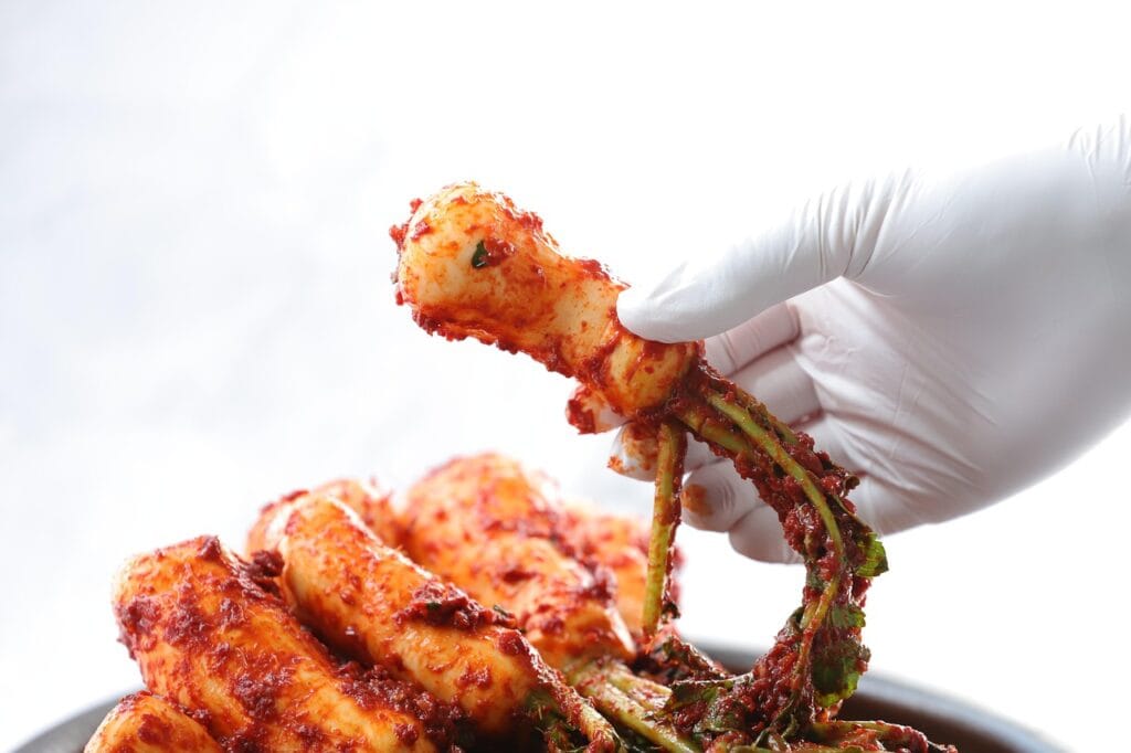 "Crunchy traditional Korean whole radish Kimchi (Chonggak-kimchi) with green stalks in spicy seasoning."