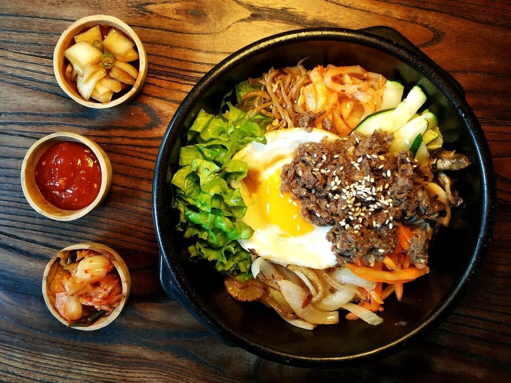 Traditional Korean Bibimbap topped with colorful vegetables, Gochujang, and a fried egg.