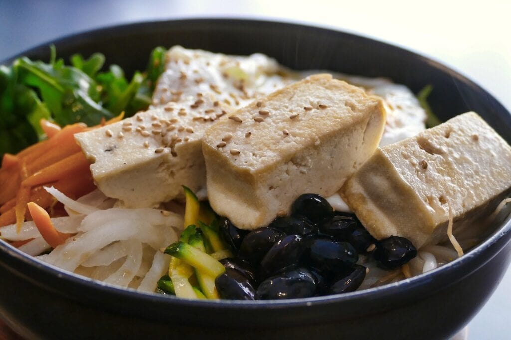 A healthy Korean Vegan Bibimbap topped with pan-fried tofu and colorful seasoned vegetables.