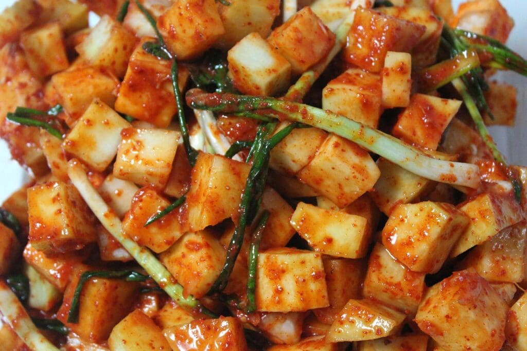 Crunchy, bite-sized traditional Korean cubed radish Kimchi (Kkakdugi) coated in spicy red chili seasoning.