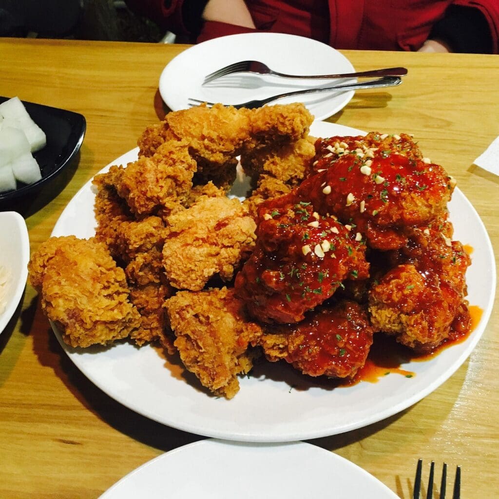 A half-and-half platter of crispy golden fried chicken and glossy, sweet and spicy seasoned chicken (Yangnyeom-chicken).