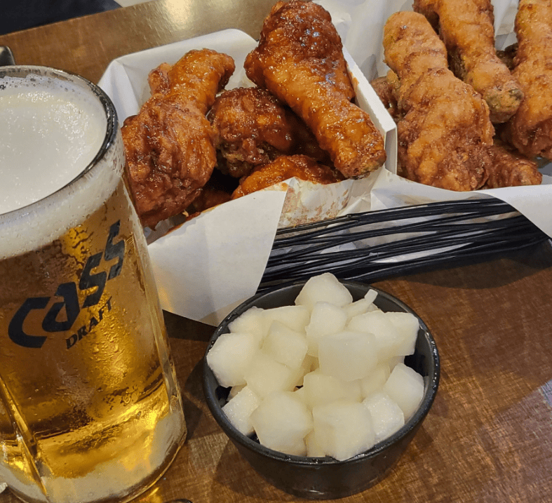 A full Chimaek set featuring savory soy and garlic fried chicken, crunchy pickled radish, and a refreshing glass of draft beer.