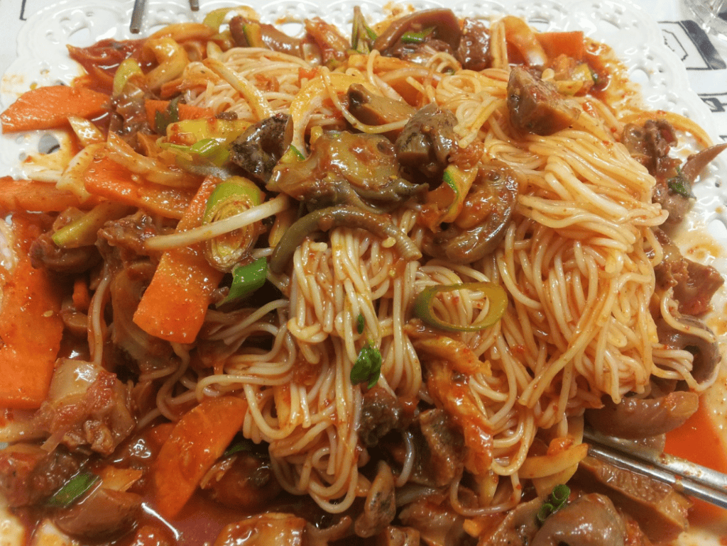 Spicy sea snail salad (Golbaengi-muchim) with fresh vegetables and white thin noodles (Somyeon).